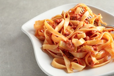 Photo of Plate with delicious pasta bolognese on grey background