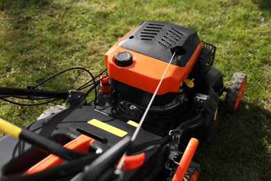 Photo of Modern lawn mower on green grass outdoors