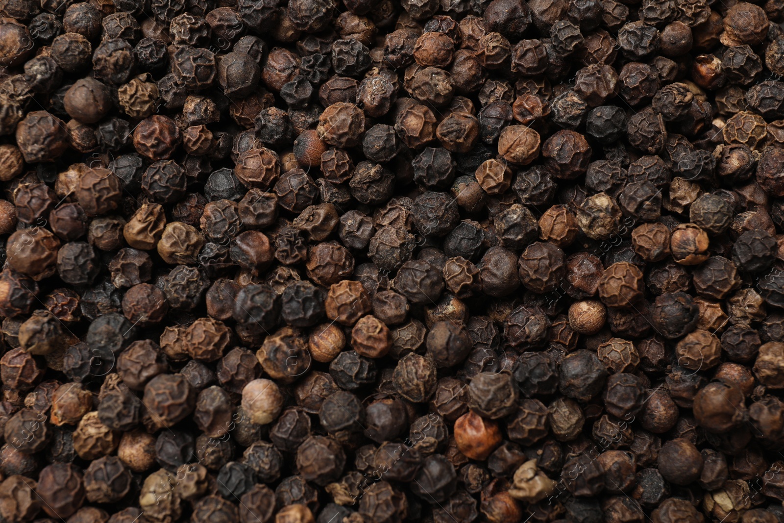 Photo of Aromatic spice. Black peppercorns as background, top view