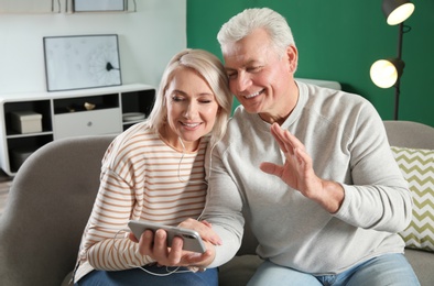 Photo of Mature couple using video chat on mobile phone at home