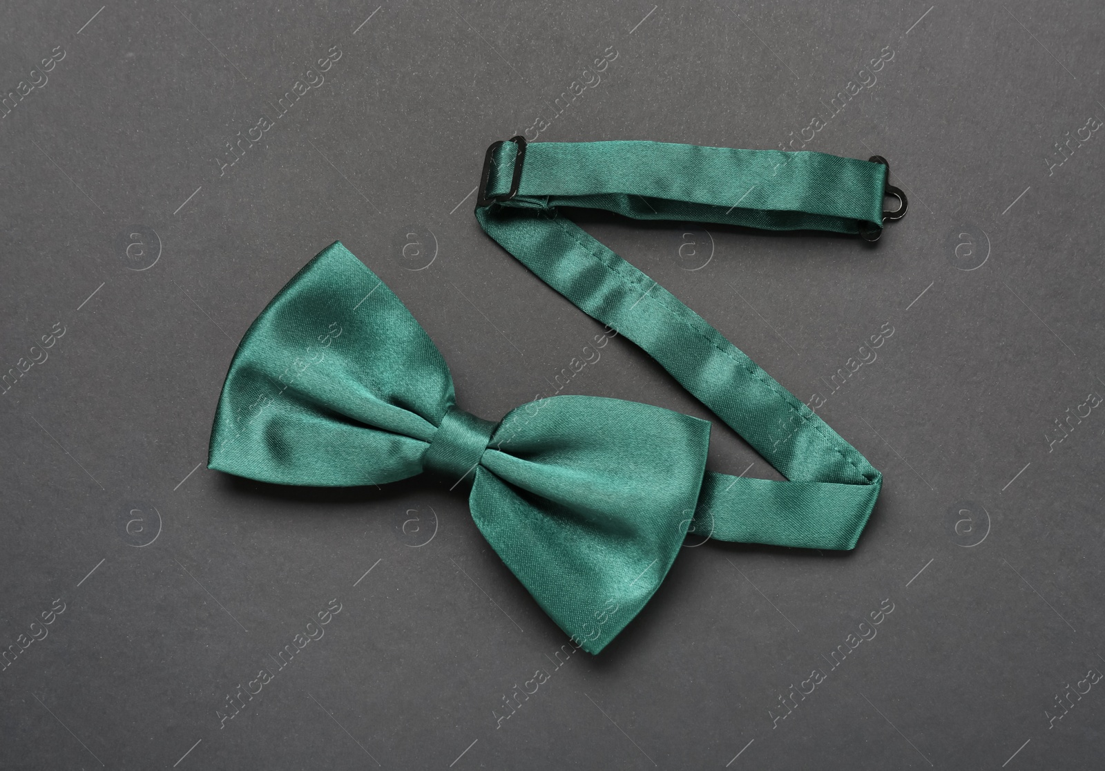 Photo of Stylish green satin bow tie on dark background, top view
