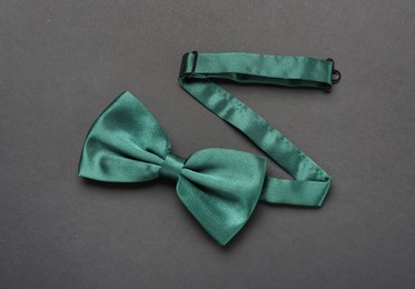 Stylish green satin bow tie on dark background, top view