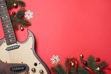 Photo of Christmas music. Flat lay composition with guitar and fir tree branches on red background, space for text