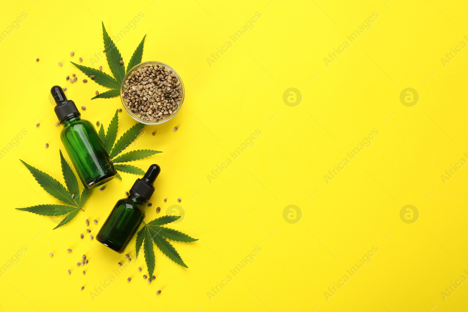 Photo of CBD oil, THC tincture, hemp leaves and grains on yellow background, flat lay. Space for text