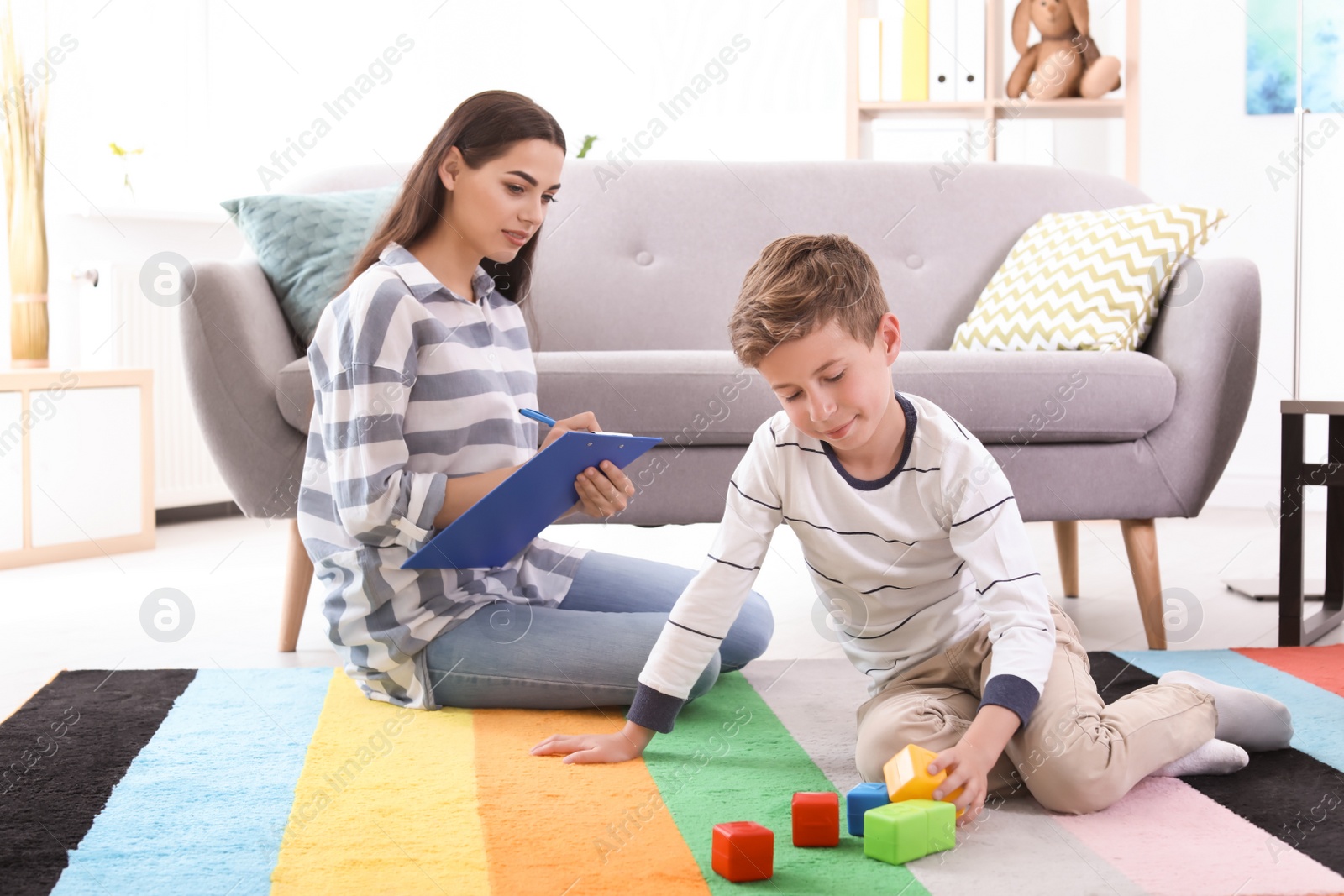 Photo of Boy playing with cubes and child psychologist in office