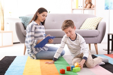 Boy playing with cubes and child psychologist in office