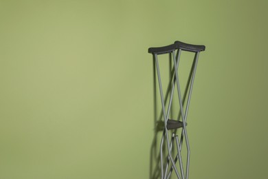 Photo of Pair of axillary crutches on light green background. Space for text