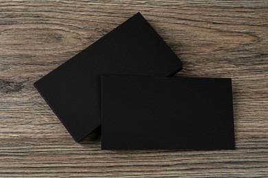 Blank black business cards on wooden background, flat lay. Mockup for design