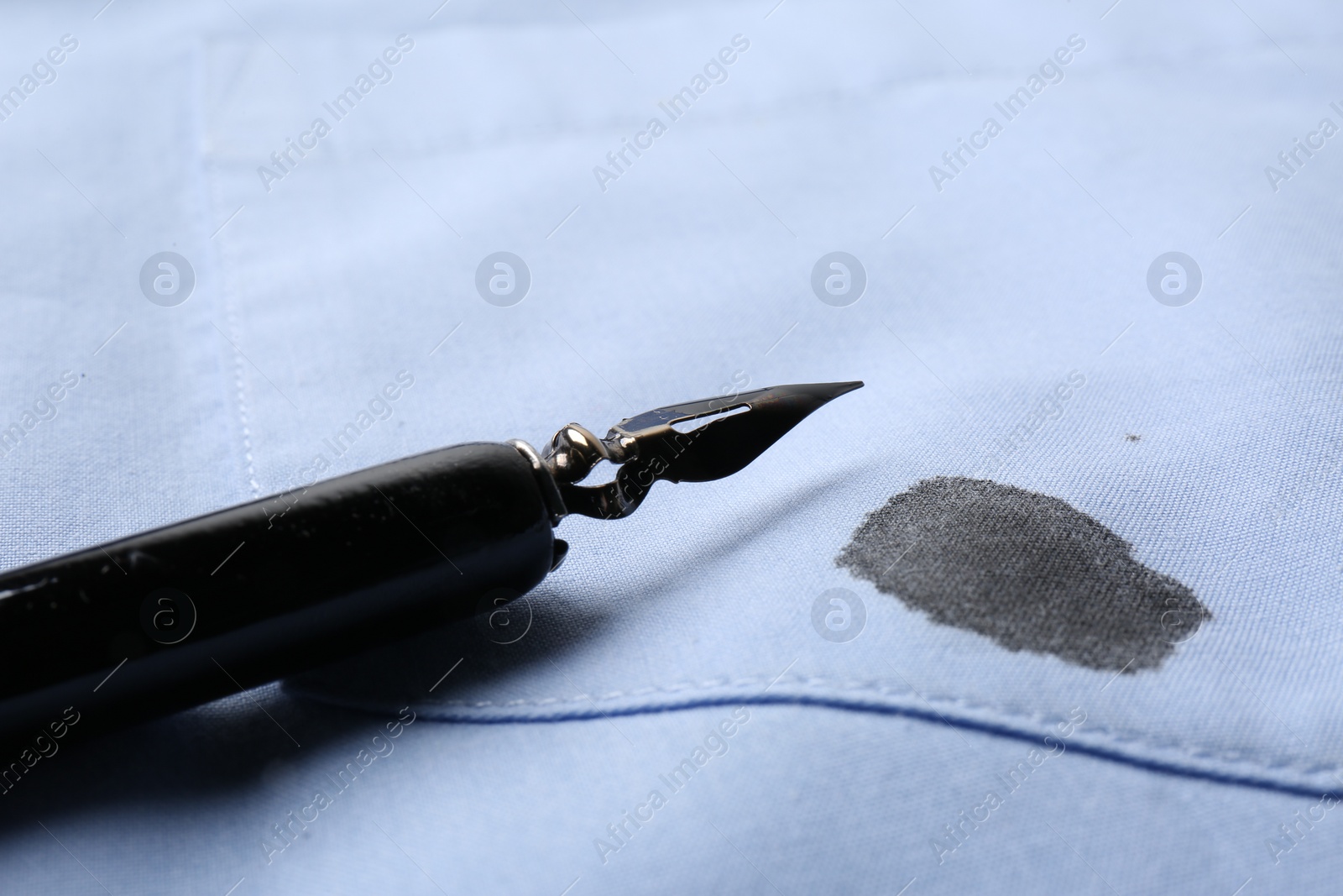 Photo of Black ink stain on light blue shirt and pen