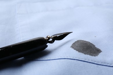 Photo of Black ink stain on light blue shirt and pen