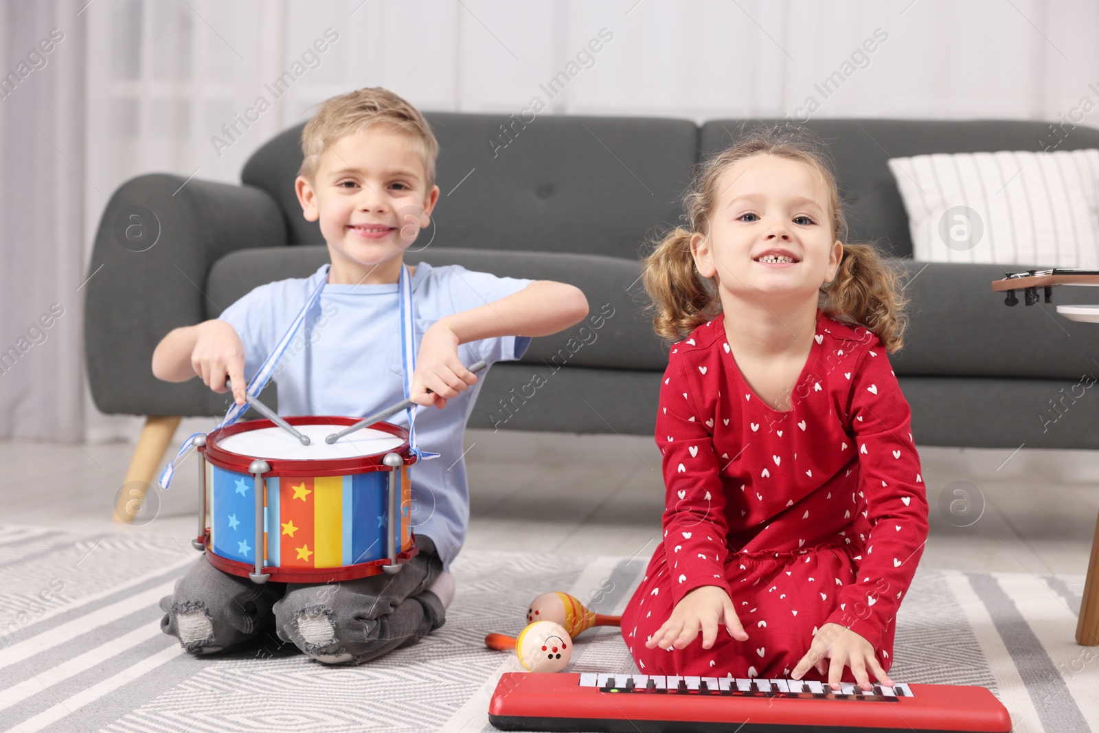 Photo of Little children playing toy musical instruments at home