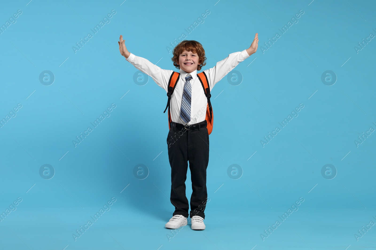 Photo of Happy schoolboy with backpack on light blue background