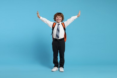 Photo of Happy schoolboy with backpack on light blue background