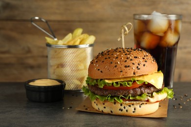 Photo of Burger with delicious patty, soda drink, french fries and sauce on gray table