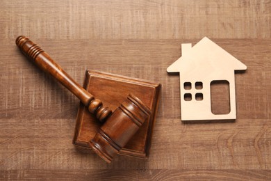 Photo of Law concept. Gavel and figure of house on wooden table, top view