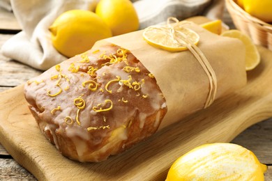 Wrapped tasty lemon cake with glaze on table, closeup