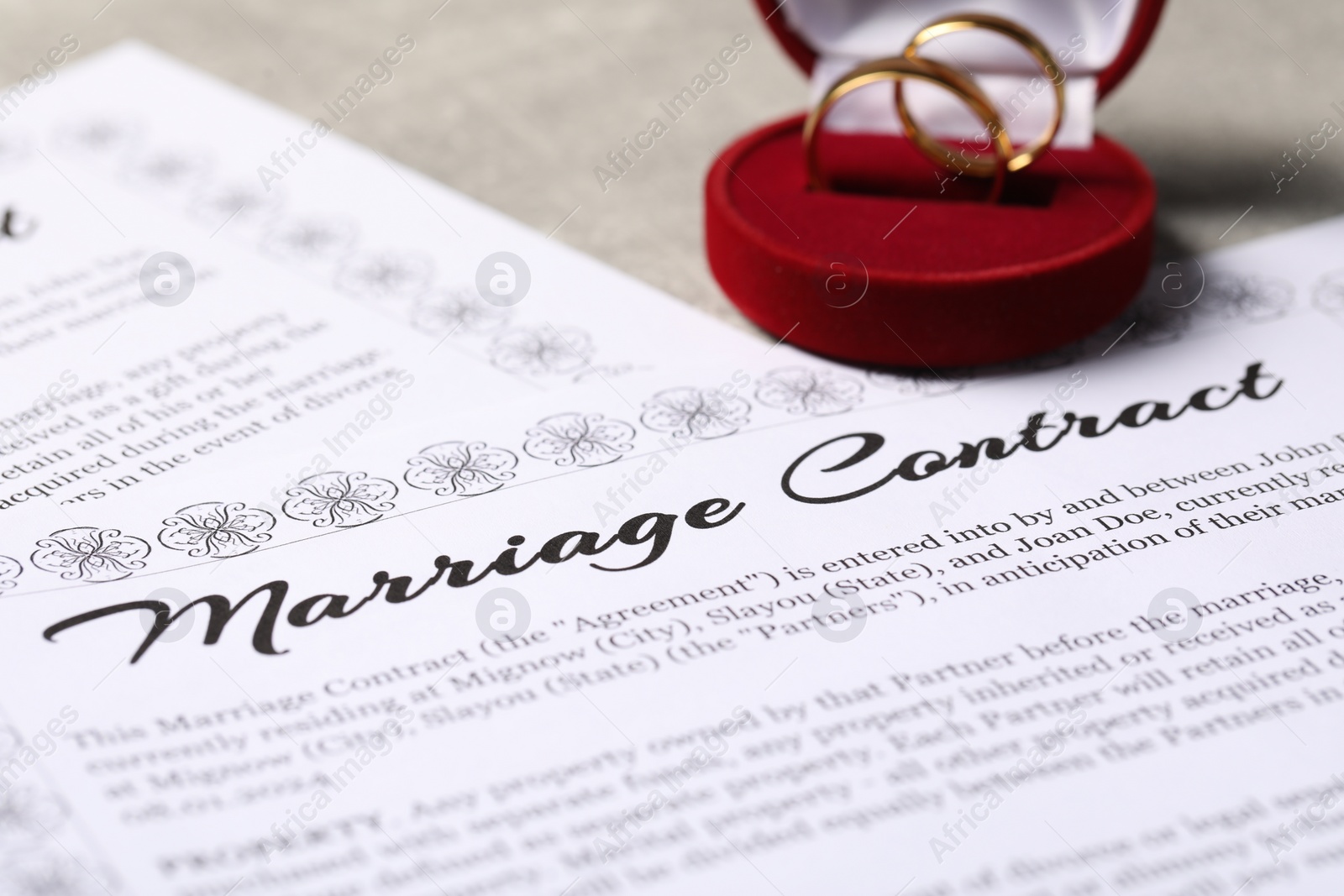 Photo of Marriage contract and golden wedding rings on grey table, closeup