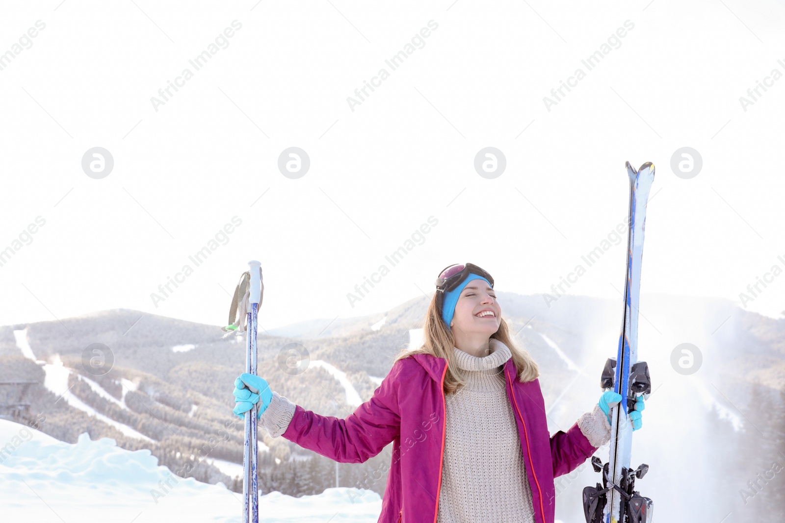 Photo of Happy young woman with ski equipment spending winter vacation in mountains. Space for text