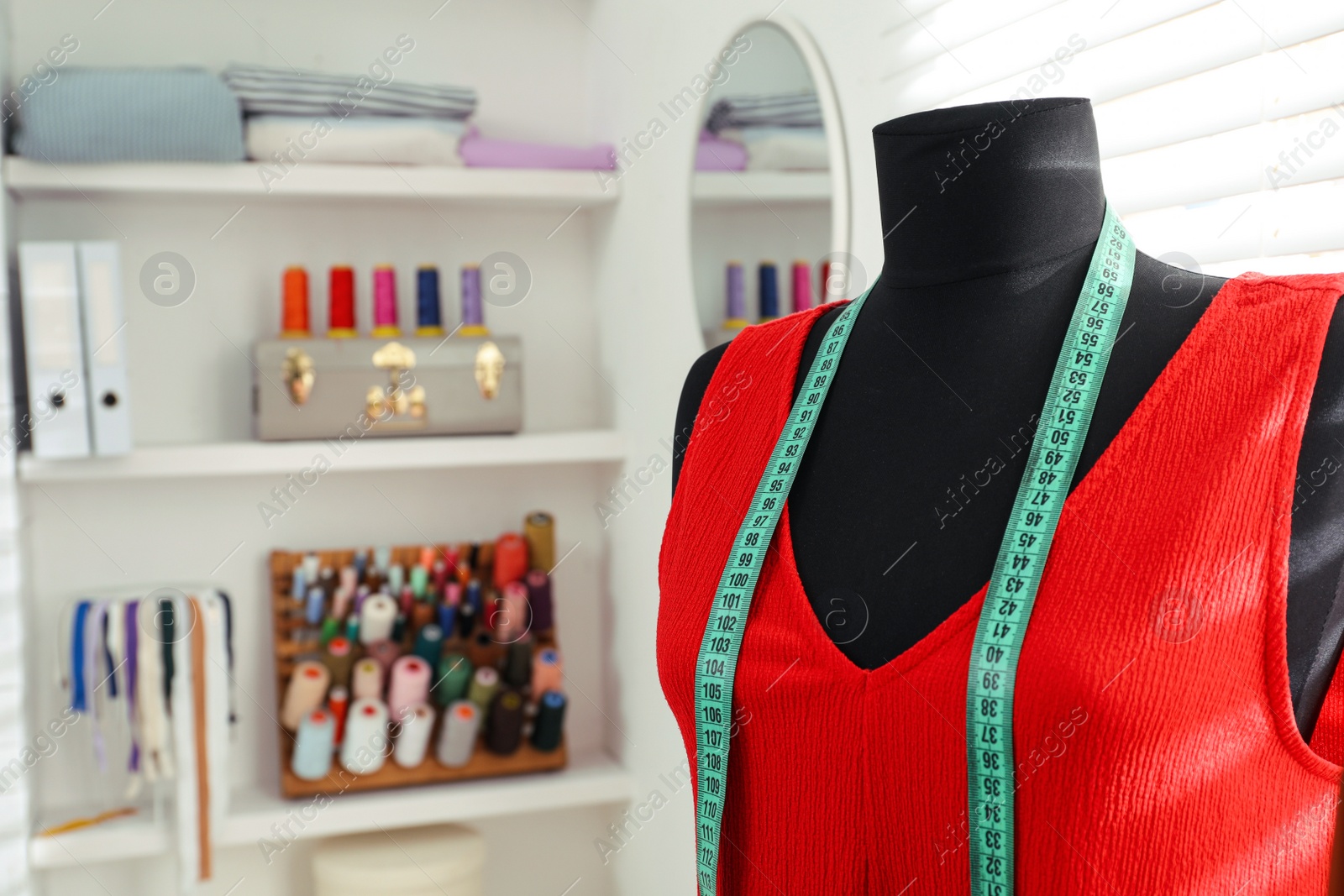 Photo of Mannequin with dress and measuring tape in tailor studio. Space for text