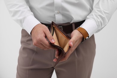 Man with empty wallet against light background, closeup