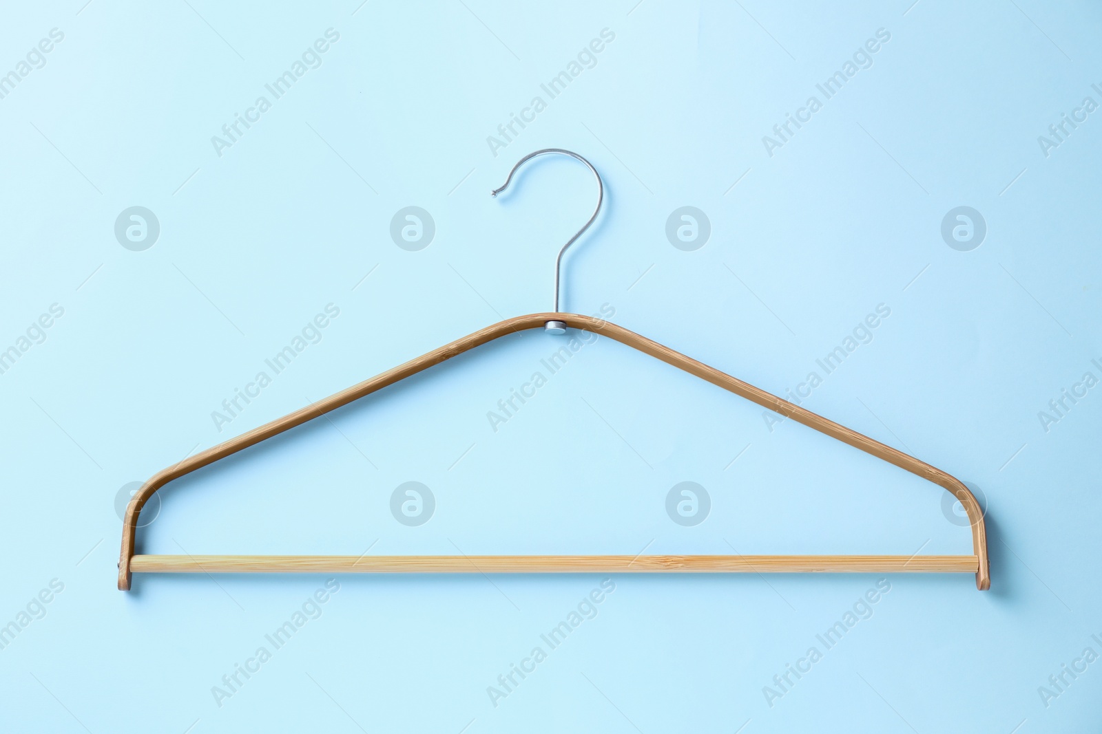 Photo of One wooden hanger on light blue background, top view