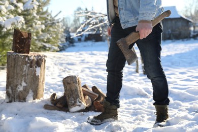 Man with axe and pile of wood outdoors on sunny winter day, closeup