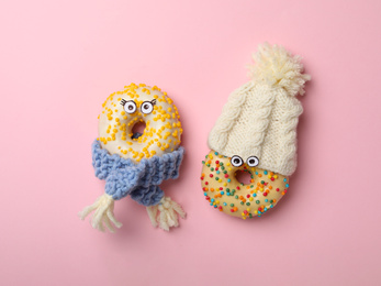 Photo of Funny faces made with donuts and warm clothes on pink background