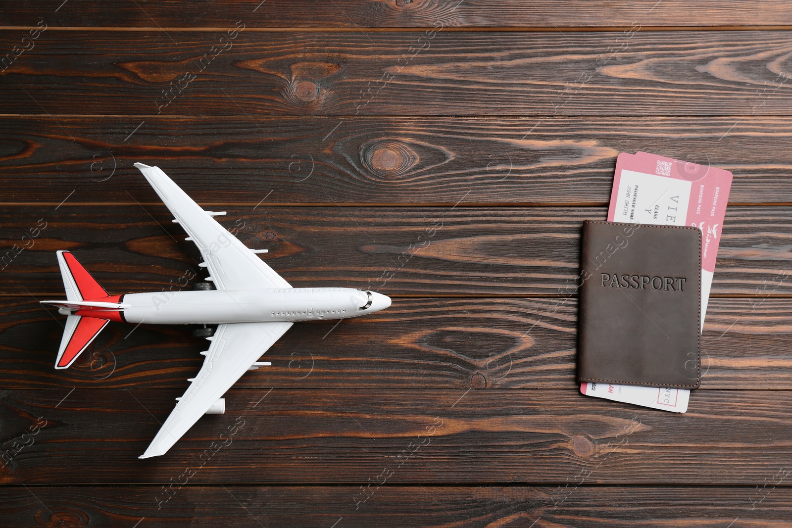 Photo of Toy airplane and passport with tickets on wooden background, flat lay