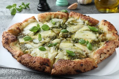 Photo of Delicious pizza with pesto, cheese and basil on grey table, closeup