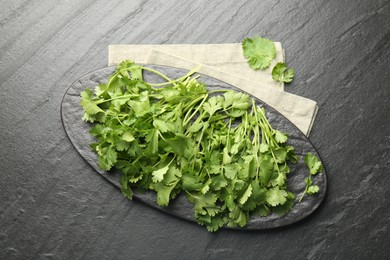 Photo of Fresh coriander on dark gray textured table, top view