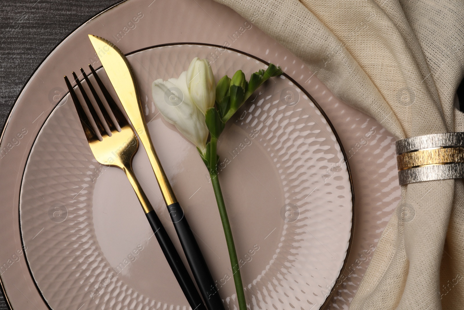 Photo of Stylish table setting. Plates, cutlery, napkin and floral decor on background, top view