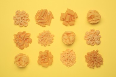 Photo of Different types of pasta on yellow background, flat lay
