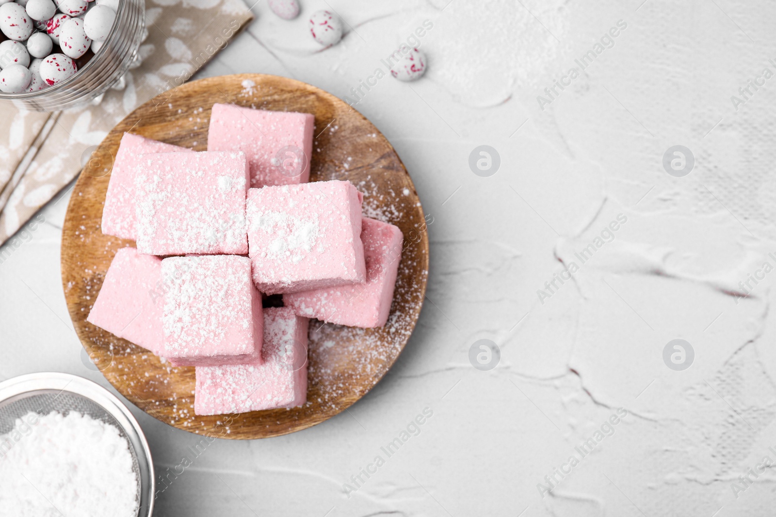 Photo of Tasty marshmallows with powder sugar on white textured table, flat lay. Space for text