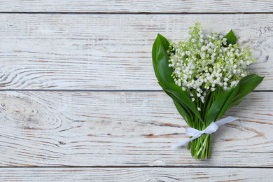 Photo of Beautiful lily of the valley flowers on white wooden table, top view. Space for text