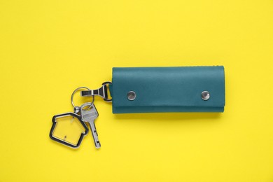 Photo of Leather case with key on yellow background, top view