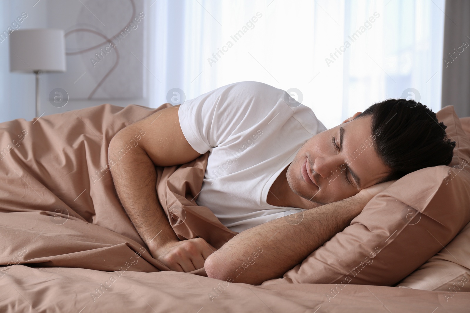 Photo of Man sleeping in comfortable bed with beige linens