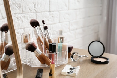 Organizer with cosmetic products for makeup on table near brick wall