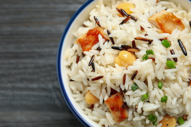 Photo of Delicious rice pilaf with chicken on black wooden table, closeup