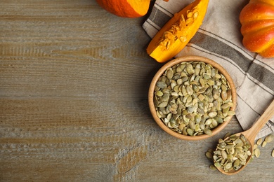 Photo of Flat lay composition with raw pumpkin seeds on wooden table, space for text