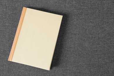 Photo of Hardcover book on grey fabric, top view. Space for text