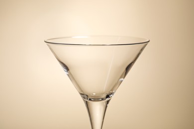 Elegant empty martini glass on beige background, closeup