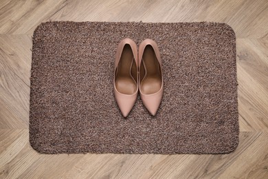 Photo of Stylish door mat and shoes on wooden floor, top view