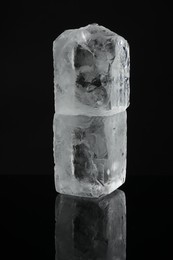 Photo of Blocks of clear ice on black mirror surface