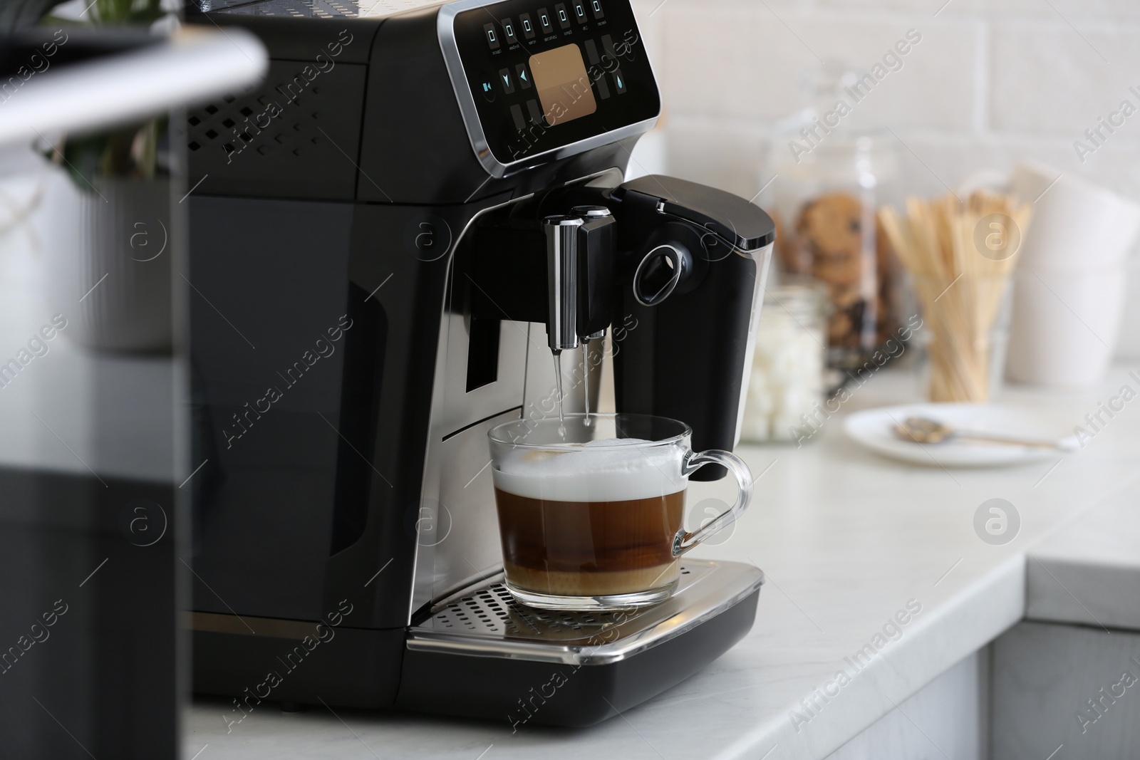 Photo of Modern electric espresso machine making coffee with milk on white marble countertop in kitchen
