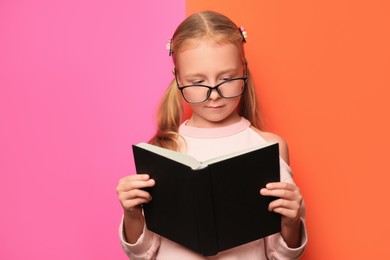 Photo of Cute little girl in glasses with book on colorful background