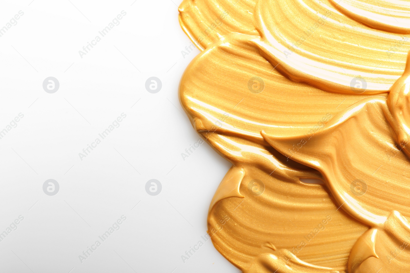 Photo of Strokes of gold paint isolated on white, top view