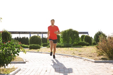 Sporty man running outdoors on sunny morning