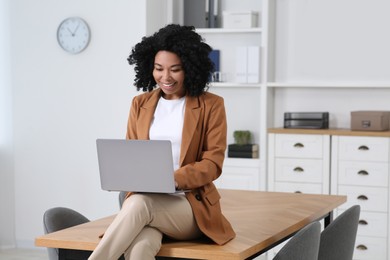 Photo of Smiling young businesswoman using laptop in modern office
