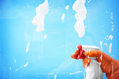 Photo of Woman cleaning glass against color background