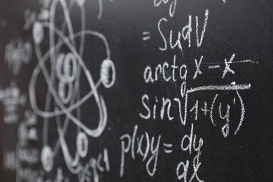 Photo of Many different physical formulas written with chalk on blackboard, closeup